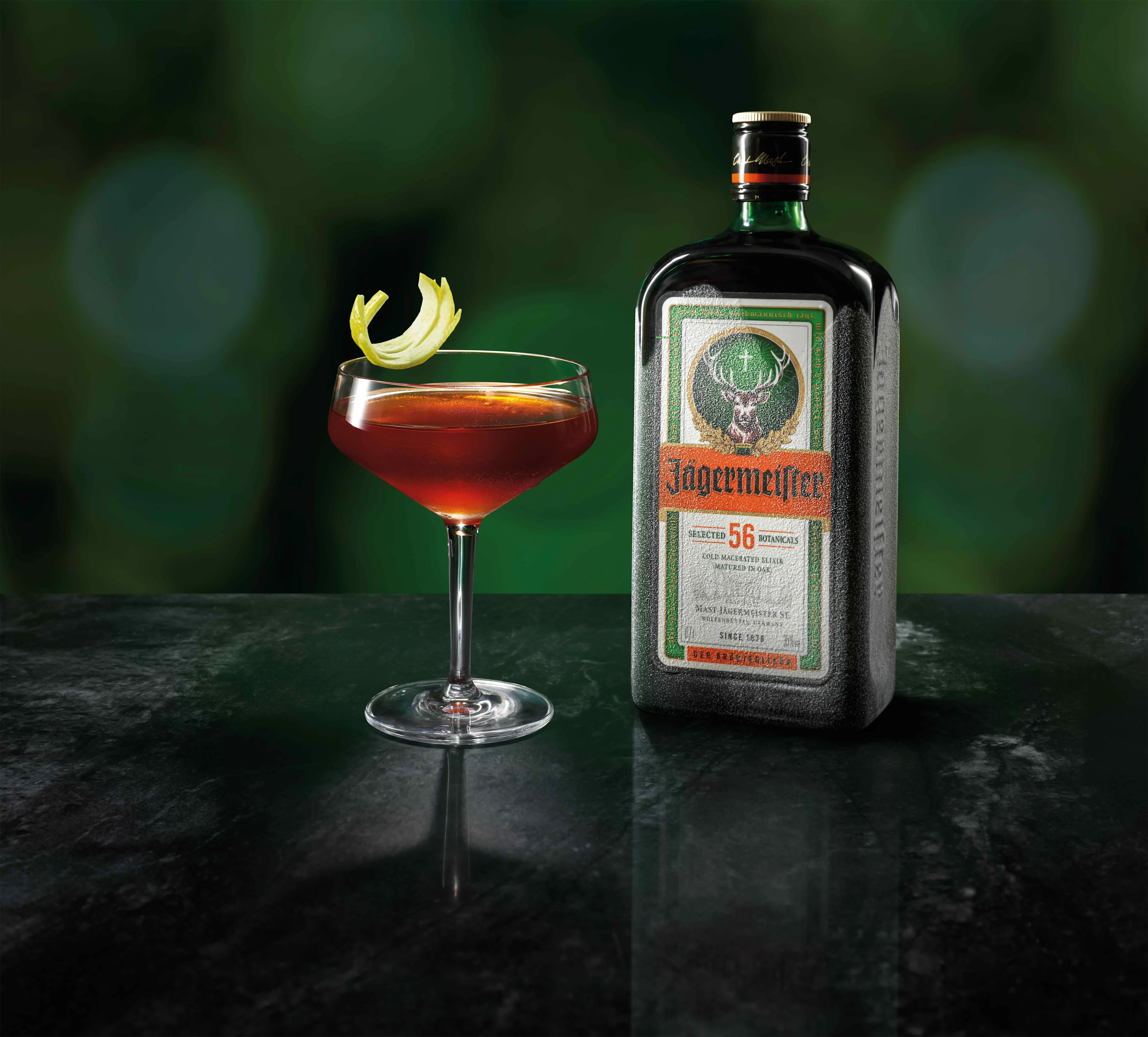 A glass of Jägermeister Count Mast in front of a Jägermeister bottle