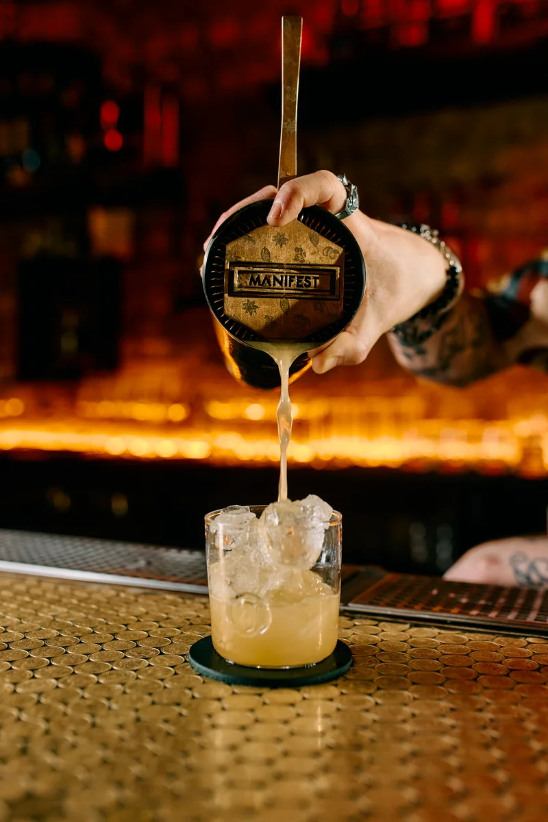 A glass of Jägermeister Manifest Sour in front of a Jägermeister Manifest bottle